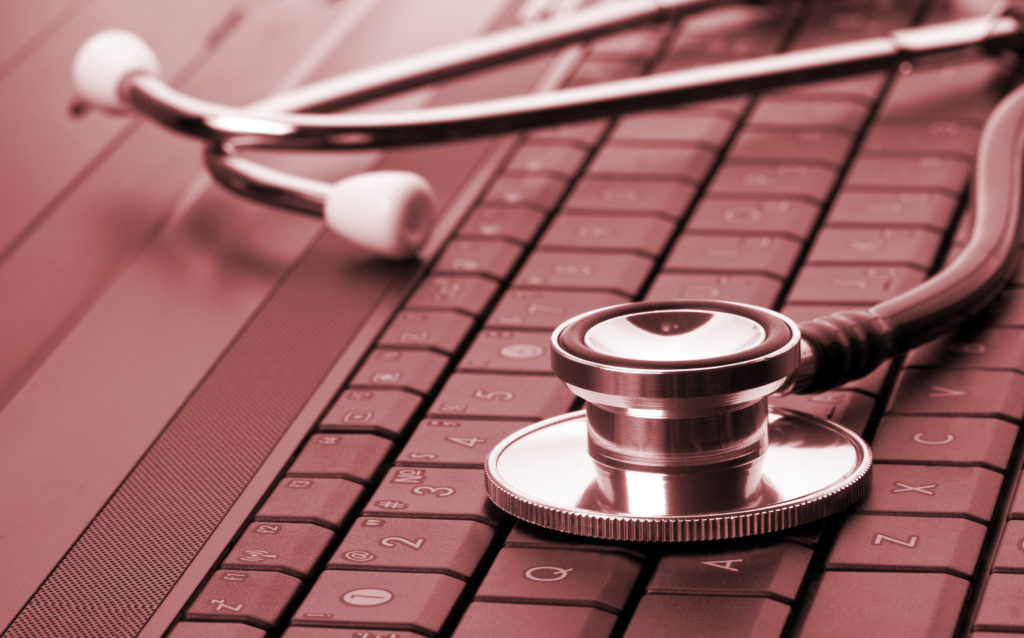 Medical stethoscope on laptop keyboard. Toned in red